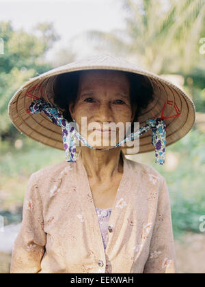 Ritratto di donna anziana che lavorano in abito tradizionale e bambù hat, Delta del Mekong Foto Stock
