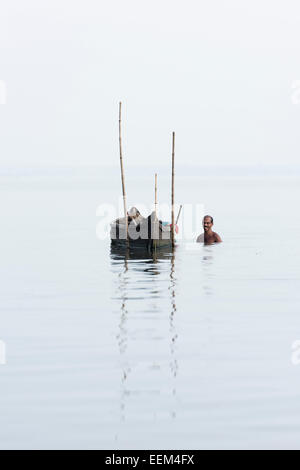Il Cockle picker a bordo della sua barca, Lago Vembanad, Kerala, India Foto Stock
