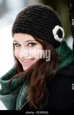 Sorridente giovane donna che indossa un cappello e sciarpa in inverno, ritratto Foto Stock