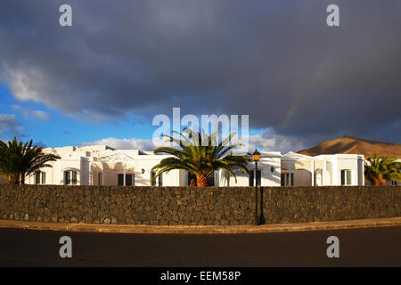 Hotel e complesso di appartamenti nella luce della sera, tipiche casette bianche dietro un muro a secco fatti di rocce laviche, con Canary Foto Stock