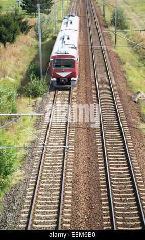 Vista aerea di un treno in arrivo con due vetture passeggeri su una stazione ferroviaria elettrificata rotta Foto Stock
