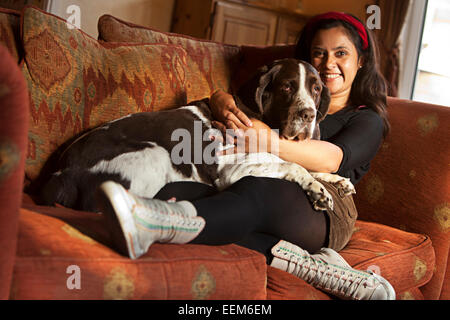Donna seduta sul divano con il suo cane Foto Stock