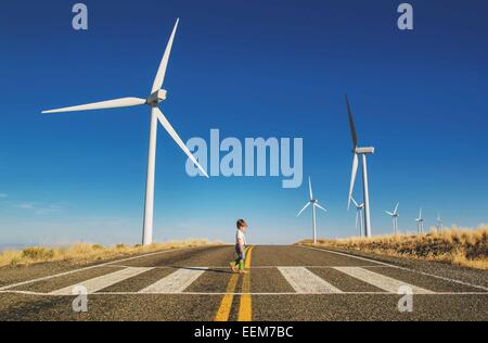 Ragazzo che attraversa una strada vicino a un'azienda eolica, Stati Uniti Foto Stock