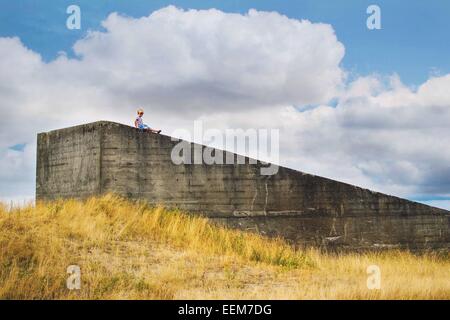 Ragazzo seduto su un muro di cemento Foto Stock