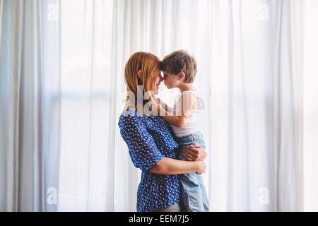 Madre e figlio faccia a faccia vicino a una finestra Foto Stock