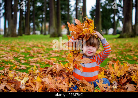 Ragazzo che gioca con foglie d'autunno nel giardino, Stati Uniti Foto Stock