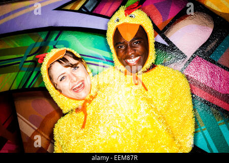 Matura in costumi di pollo sorridendo vicino al muro di graffiti Foto Stock