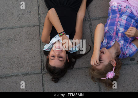 Due ragazze che giace a terra a ridere Foto Stock