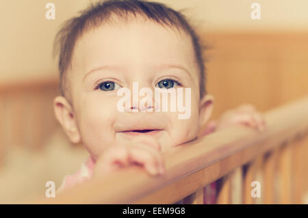 Baby girl (6-11 mesi) Guardando sopra la sua culla Foto Stock