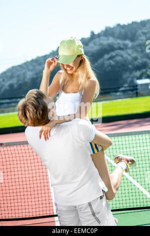 I giovani coniugi giocando a tennis in bianco sportwear sul campo da tennis esterno in estate Foto Stock