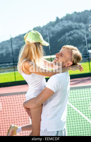 I giovani coniugi giocando a tennis in bianco sportwear sul campo da tennis esterno in estate Foto Stock