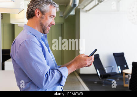 Imprenditore caucasico utilizzando il cellulare in ufficio Foto Stock