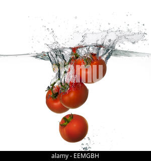 Primo piano della fresca e pomodori di salute di cadere in acqua chiara con grande splash isolati su sfondo bianco Foto Stock