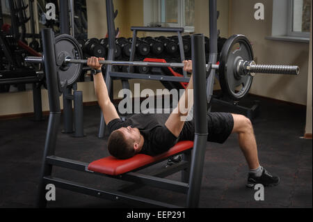 Giovane uomo facendo la pressa da banco allenamento in palestra Foto Stock