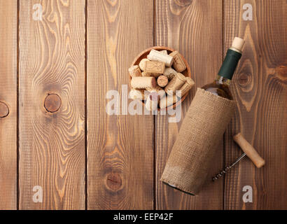 Vino bianco bottiglia, ciotola con tappi e cavatappi. Vista da sopra su tavola in legno rustico sfondo Foto Stock