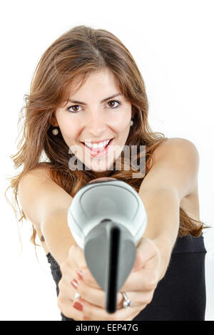 Sorridente e felice professional caucasian brunette femmina azienda parrucchiere asciugacapelli come pistola e puntando alla fotocamera, isolato Foto Stock