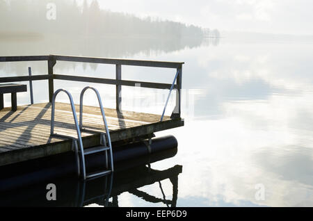 Paesaggio estivo, il lago e il molo in legno nella nebbia Foto Stock