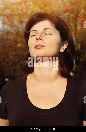 Close up ritratto di bella donna sorride con gli occhi chiusi oltre la luce solare, la meditazione per esterno Foto Stock