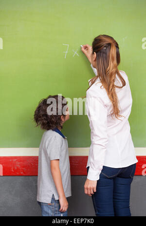 Femmina spiegando insegnante di matematica per la scuola primaria kid. Foto Stock