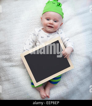 Sorridente dagli occhi blu baby boy tenendo una lavagna Foto Stock