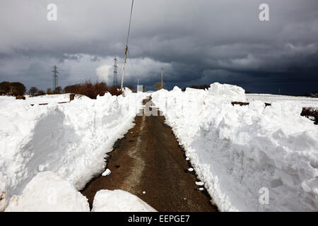 Taglio di percorso attraverso cumuli di neve durante l'inverno Irlanda del Nord Foto Stock