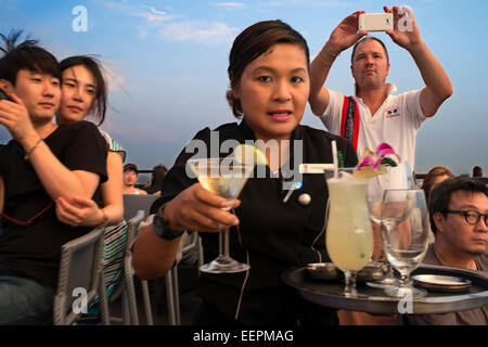 Cameriera con un cocktail in mano. Banyan Tree tetto Vertigo e Luna Bar, Ristorante, , Bangkok , Thailandia. Vista della città, Foto Stock