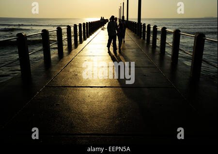 Durban, KwaZulu-Natal, Sud Africa, silhouette di gente che camminava sul molo, sole riflesso concreto di struttura Foto Stock