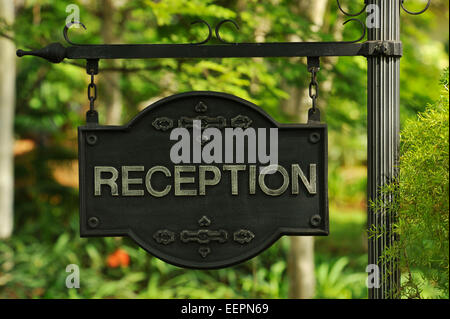 Weathered green Hotel Reception segno appeso sul palo in giardino verde Foto Stock