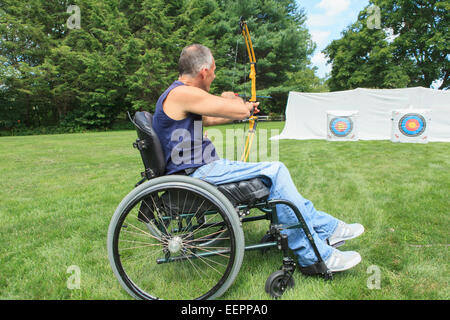 Uomo con lesioni al midollo spinale in carrozzella mirando il suo arco e la freccia per la pratica del tiro con l'arco Foto Stock