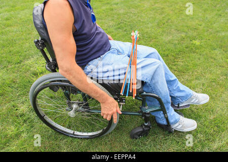 Uomo con lesioni al midollo spinale in sedia a rotelle la preparazione per la pratica del tiro con l'arco Foto Stock