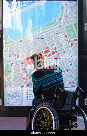 Alla moda uomo con una lesione del midollo spinale in carrozzella guardando una mappa della metropolitana della città Foto Stock