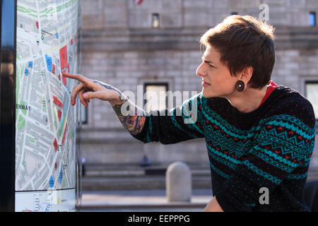 Alla moda uomo con una lesione del midollo spinale in carrozzella guardando una mappa della metropolitana della città Foto Stock