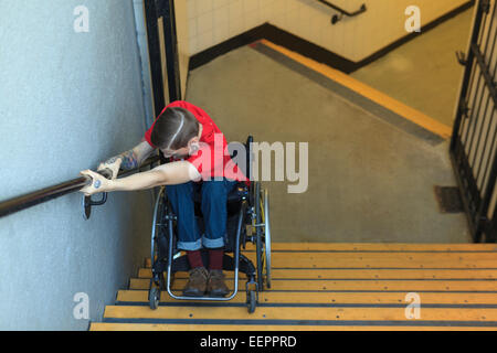 Alla moda uomo con una lesione del midollo spinale in sedia a rotelle scendendo le scale della metropolitana indietro Foto Stock