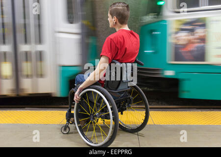 Alla moda uomo con una lesione del midollo spinale in sedia a rotelle in attesa di un treno della metropolitana Foto Stock