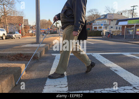 Uomo con la cecità congenita attraversando la strada con la sua canna da zucchero Foto Stock
