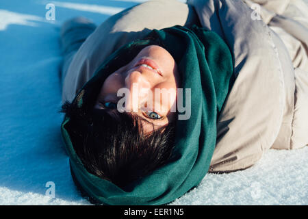 Ragazza distesa sulla neve e sorridente Foto Stock