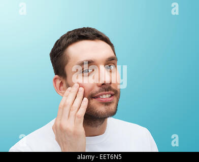 Bellissimo uomo sorridente toccando il suo volto Foto Stock