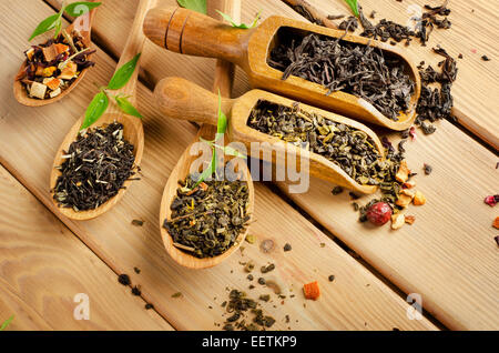 Assortimento di tè secco in cucchiaio su uno sfondo di legno. Messa a fuoco selettiva Foto Stock