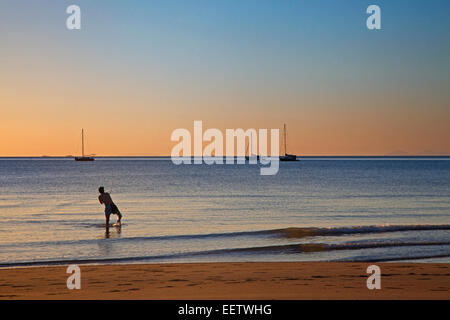 Barche a vela al tramonto e mare pescatore pesca dalla spiaggia di Baia a ferro di cavallo su Magnetic Island lungo il Mar dei Coralli, Australia Foto Stock