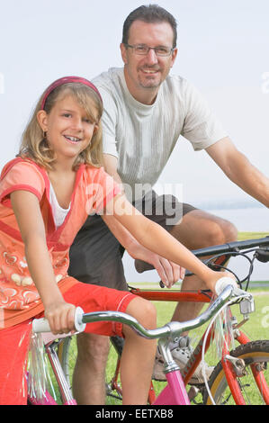 Padre e figlia con biciclette a un parco Foto Stock