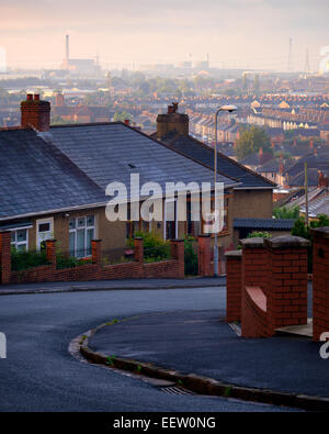 Una fila di case tipiche della città di Newport contro uno sfondo di alloggiamento e industria. Foto Stock