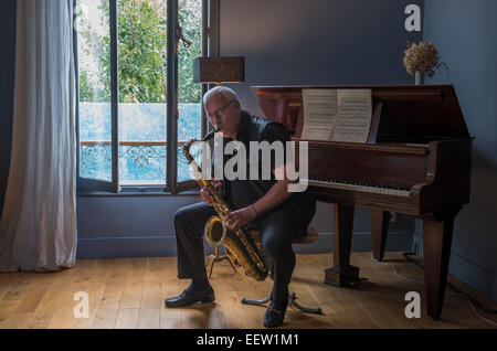 Maschio maturo giocando un sassofono in una sala della musica Foto Stock