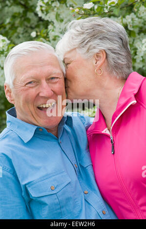 Senior donna sussurra all orecchio del marito Foto Stock
