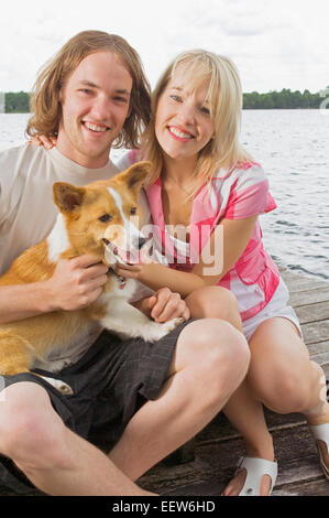 Un giovane seduto su un litorale con il loro cane Foto Stock