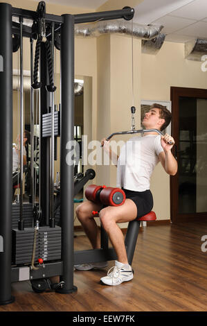 Giovane uomo facendo lats pull-down allenamento Foto Stock