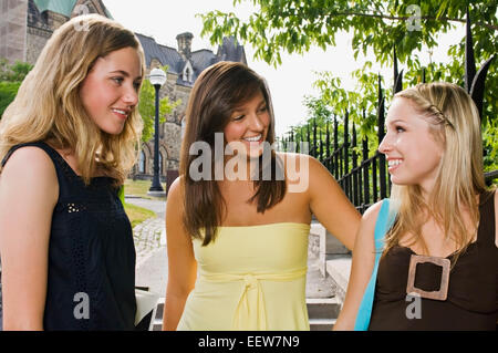 Tre ragazza amici permanente sulla strada avente una conversazione Foto Stock