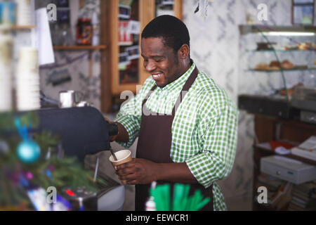 Felice afro-americano in uniforme che lavorano in cafe Foto Stock