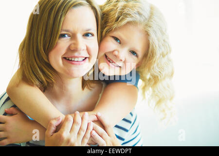 Affascinante piccolo ragazza abbracciando la madre Foto Stock