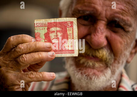 Anziani uomo cubano tenendo un 3 pesos a Bill con il ritratto di Ernesto Che Guevara in sua mano, Havana, Cuba Foto Stock