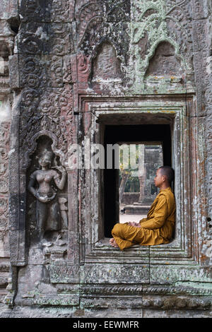 Giovane Monaco collocazione in una finestra al Ta Prohm rovinato tempio di Angkor Wat ,Cambogia Foto Stock